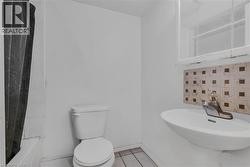 Pedestal sink with mosaic tile backsplash, adjacent to a toilet and a tiled shower stall - 