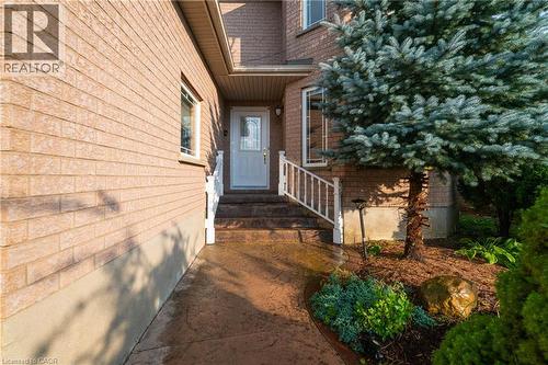 Brick exterior featuring a white entry door with decorative glass, white handrails, and a stained concrete pathway - 888 Paisley Road, Guelph, ON - Outdoor