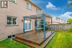 Expansive backyard featuring a multi-level wood deck with a pergola, a manicured lawn, and a privacy fence - 