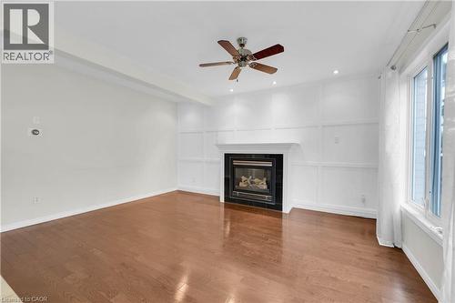 Living area featuring wood-finish flooring and a white paneled accent wall with a built-in fireplace - 888 Paisley Road, Guelph, ON - Indoor With Fireplace