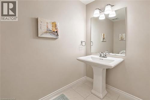 Pedestal sink with chrome faucet, large vanity mirror, and three-light fixture - 133 St Leger Street, Kitchener, ON - Indoor Photo Showing Bathroom