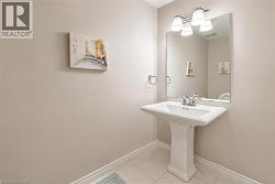 Pedestal sink with chrome faucet, large vanity mirror, and three-light fixture - 