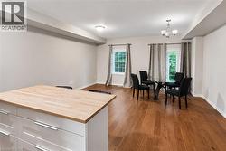 Open-concept living area featuring rich wood-finish flooring, white baseboards, and neutral wall tones - 
