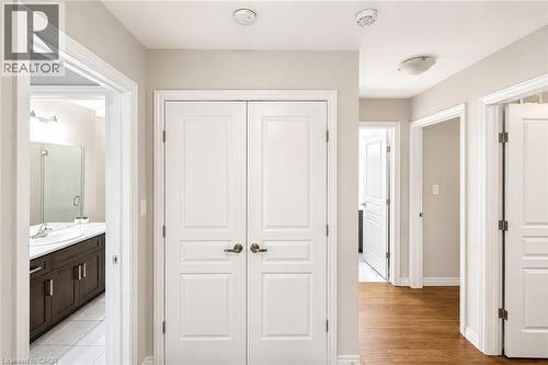 Hallway featuring white paneled doors, light neutral wall paint, and wood-finish flooring - 133 St Leger Street, Kitchener, ON - Indoor