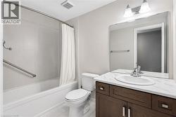 Bathroom featuring a dark wood-finish vanity with an undermount sink, a white countertop, and a large wall-mounted mirror - 