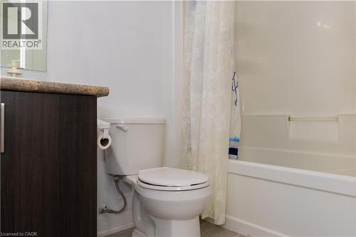 Bathroom featuring a dark wood-finish vanity with a speckled countertop, a white toilet, and a white tub with integrated shelving - 190 Century Hill Drive Unit# A5, Kitchener, ON - Indoor Photo Showing Bathroom
