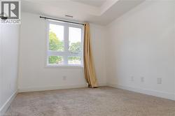 Carpeted room featuring a large window with white framing and a black curtain rod - 
