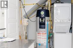 Dedicated utility area featuring a stacked washer and dryer, a water heater, and visible plumbing - 