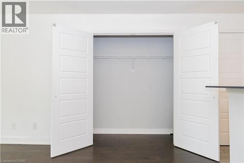 Closet space featuring white bi-fold paneled doors, wire shelving, dark wood-finish flooring, and white baseboards - 190 Century Hill Drive Unit# A5, Kitchener, ON - Indoor Photo Showing Other Room