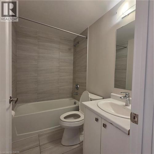 Bathroom featuring a white bathtub, ceramic tile surround, white toilet, and a vanity with an integrated sink and base cabinetry - 20 Palace Place Unit# E9, Kitchener, ON - Indoor Photo Showing Bathroom