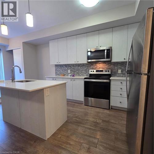 Contemporary kitchen featuring wood-finish flooring, white cabinetry, and stainless steel appliances - 20 Palace Place Unit# E9, Kitchener, ON - Indoor Photo Showing Kitchen With Upgraded Kitchen