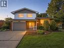 Two-story residence featuring a brick and siding exterior, an attached garage with a roll-up door, a concrete driveway, a manicured lawn, and mature landscaping - 143 Cromwell Crescent, Hamilton, ON  - Outdoor 