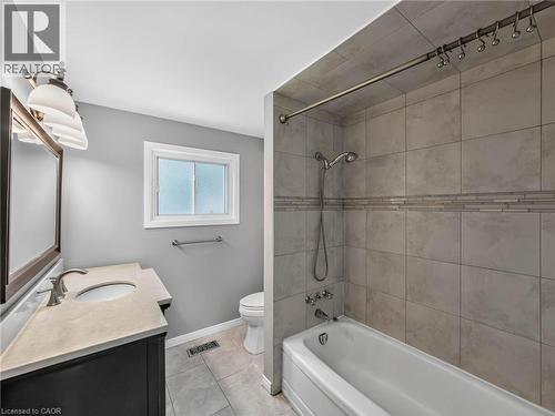 Bathroom featuring a single vanity with an integrated sink, a rectangular mirror, and an overhead light fixture - 143 Cromwell Crescent, Hamilton, ON - Indoor Photo Showing Bathroom