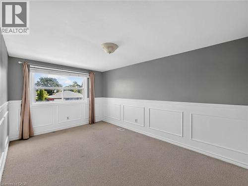 Room featuring wainscoting, neutral carpet, a large window, and a flush mount ceiling light - 143 Cromwell Crescent, Hamilton, ON - Indoor Photo Showing Other Room