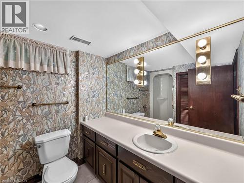 Bathroom featuring a vanity with an integrated sink, dark wood cabinetry, and a large wall-mounted mirror - 143 Cromwell Crescent, Hamilton, ON - Indoor Photo Showing Bathroom