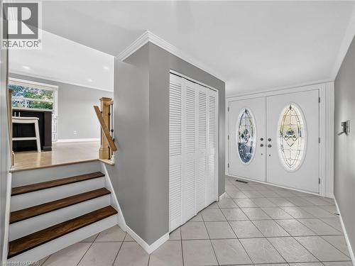 Entryway featuring double doors with decorative oval glass inserts, tile flooring, bi-fold closet doors, and crown molding - 143 Cromwell Crescent, Hamilton, ON - Indoor Photo Showing Other Room