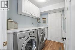 Laundry area featuring a built-in countertop, integrated sink, and white upper cabinetry - 