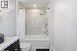 Contemporary bathroom featuring a tub/shower combination with a curved shower rod and light-toned tiled surround - 