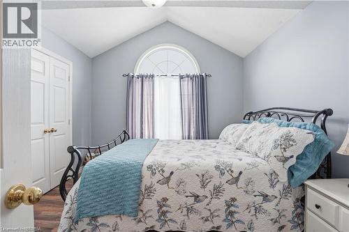 Vaulted ceiling bedroom featuring an arched window, wood-finish flooring, and double bi-fold closet doors - 25 Brian Drive, Burford, ON - Indoor Photo Showing Bedroom