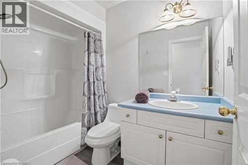Bathroom featuring a white bathtub and shower combination, a white vanity with a blue countertop, a built-in sink, and a large mirror - 25 Brian Drive, Burford, ON - Indoor Photo Showing Bathroom