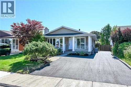 Ranch-style exterior featuring a covered front porch with white railings and columns, a paved driveway, and established landscaping - 101 Loyalist Drive, Hamilton, ON - Outdoor With Deck Patio Veranda