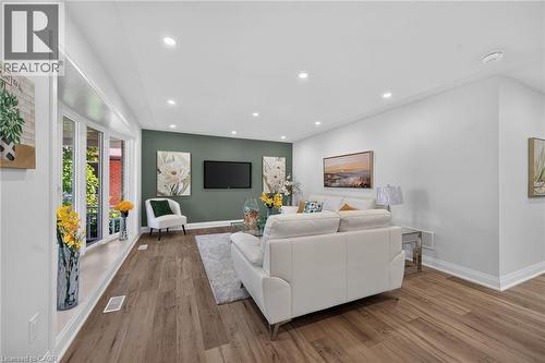 Living area featuring wood-finish flooring, a prominent bay window, recessed lighting, white baseboards, and a contrasting accent wall - 101 Loyalist Drive, Hamilton, ON - Indoor Photo Showing Living Room