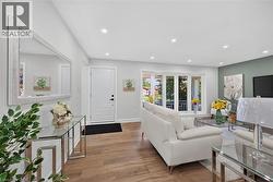 Bright living area featuring wood-finish flooring, recessed lighting, a front entry door, a bay window, and a feature wall with accent paint - 
