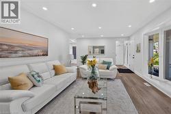 Spacious living area featuring recessed lighting, large picture windows, wood-finish flooring, and a white interior color palette - 