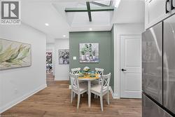 Dining area featuring a skylight with exposed beams, wood-finish flooring, recessed lighting, and a contrasting accent wall - 
