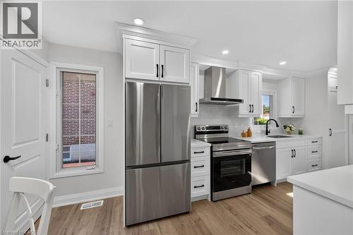 Modern kitchen featuring white shaker cabinetry, stainless steel appliances, wood-finish flooring, recessed lighting, and a black gooseneck faucet - 101 Loyalist Drive, Hamilton, ON - Indoor Photo Showing Kitchen