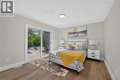 Sliding glass door opening to an outdoor pool area, featuring wood-finish flooring, white baseboards, and neutral wall tones - 101 Loyalist Drive, Hamilton, ON - Indoor Photo Showing Bedroom