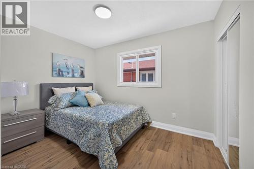 Room featuring wood-finish flooring, a double window, and a sliding mirrored closet door - 101 Loyalist Drive, Hamilton, ON - Indoor Photo Showing Bedroom