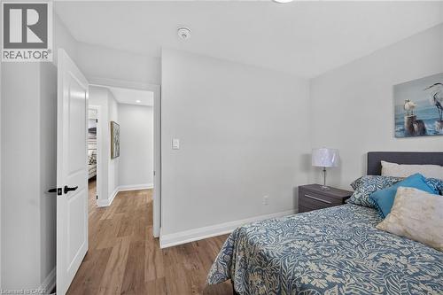 Bedroom featuring wood-finish flooring, white baseboards, and a solid core interior door with matte black hardware - 101 Loyalist Drive, Hamilton, ON - Indoor Photo Showing Bedroom