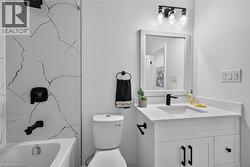 Bathroom featuring a white vanity with an integrated sink, matte black faucet, and a framed mirror - 