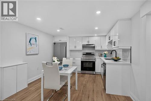Modern kitchen featuring stainless steel appliances, white cabinetry, and wood-finish flooring - 101 Loyalist Drive, Hamilton, ON - Indoor Photo Showing Kitchen
