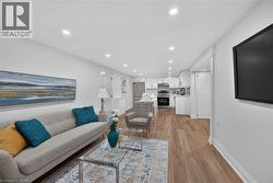Open-concept living space featuring wood-finish flooring, recessed lighting, and white walls - 
