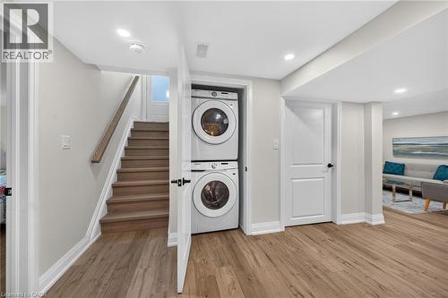 Laundry area featuring stacked appliances, wood-finish flooring, recessed lighting, white trim, and light gray wall paint - 101 Loyalist Drive, Hamilton, ON - Indoor Photo Showing Laundry Room