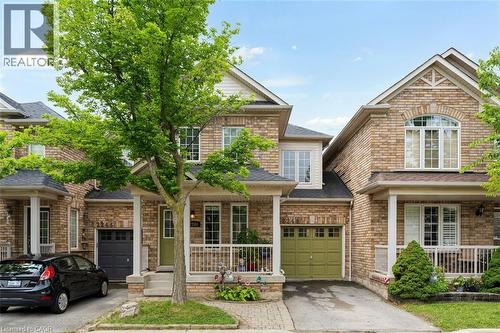 Brick facade residence featuring a covered front porch, an attached single-car garage, and a mature tree providing natural shade - 2248 Seton Crescent, Burlington, ON - Outdoor With Facade
