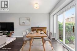 Dining area featuring dark wood-finish flooring, light grey wall paint, and a sliding glass door - 