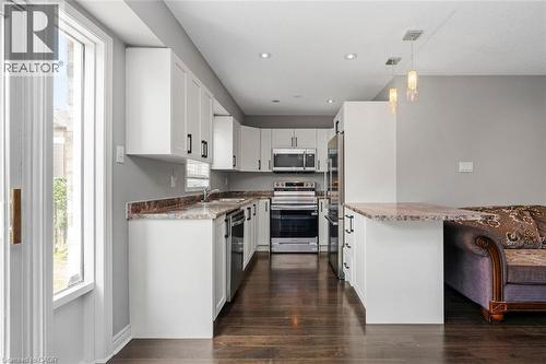 Modern kitchen featuring white cabinetry with dark hardware, stainless steel appliances, recessed lighting, and wood-finish flooring - 2248 Seton Crescent, Burlington, ON - Indoor Photo Showing Kitchen With Stainless Steel Kitchen