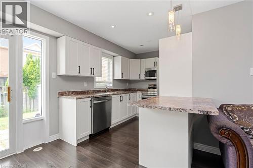 Contemporary kitchen featuring white cabinetry, dark wood-finish flooring, a stainless steel dishwasher, and a built-in microwave - 2248 Seton Crescent, Burlington, ON - Indoor Photo Showing Kitchen With Stainless Steel Kitchen With Upgraded Kitchen