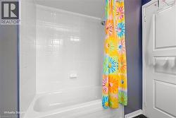 White ceramic tile shower surround with integrated soap dish, a white porcelain tub, and a chrome shower head - 