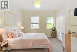 Bedroom featuring two windows with blinds, a ceiling light fixture, a paneled door, and neutral-toned wall paint - 