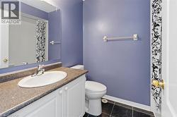 Bathroom featuring a white vanity with a speckled countertop, an integrated sink, and white cabinetry - 