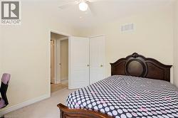 Neutral-toned bedroom featuring carpet flooring, white baseboards, and a ceiling fan - 