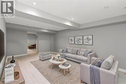 Spacious living area featuring light wood-finish flooring, recessed lighting, and neutral gray walls - 
