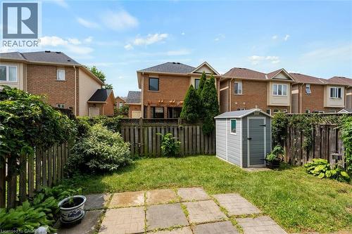 Fenced backyard featuring a compact storage shed, mature perimeter plantings, and concrete patio pavers - 2248 Seton Crescent, Burlington, ON - Outdoor
