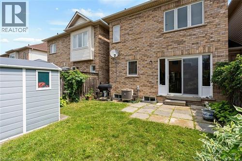 Expansive backyard featuring a manicured lawn, a detached storage shed, a stone paver patio, and sliding glass door access to the interior - 2248 Seton Crescent, Burlington, ON - Outdoor With Exterior
