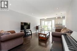 Spacious open-concept living area featuring dark wood-finish flooring, recessed lighting, and light gray walls - 