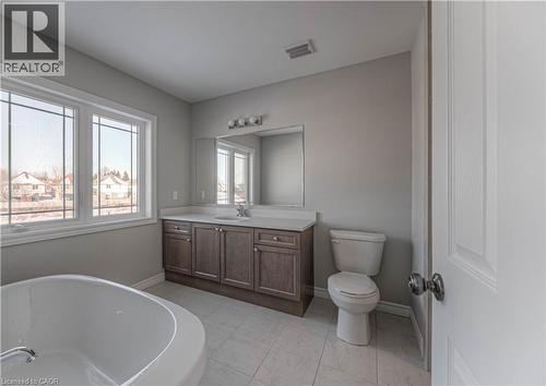 Contemporary bathroom featuring a large window, tiled flooring, an oval soaking tub, a single-sink vanity with storage, and a toilet - 44 Harrison Drive, Cambridge, ON - Indoor Photo Showing Bathroom